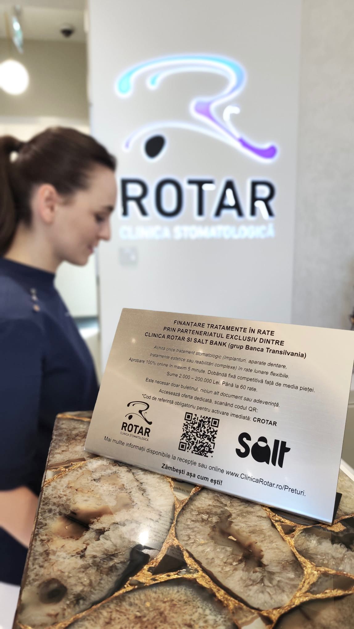 Staff member presenting financing plaque with QR code to dental clinic patients